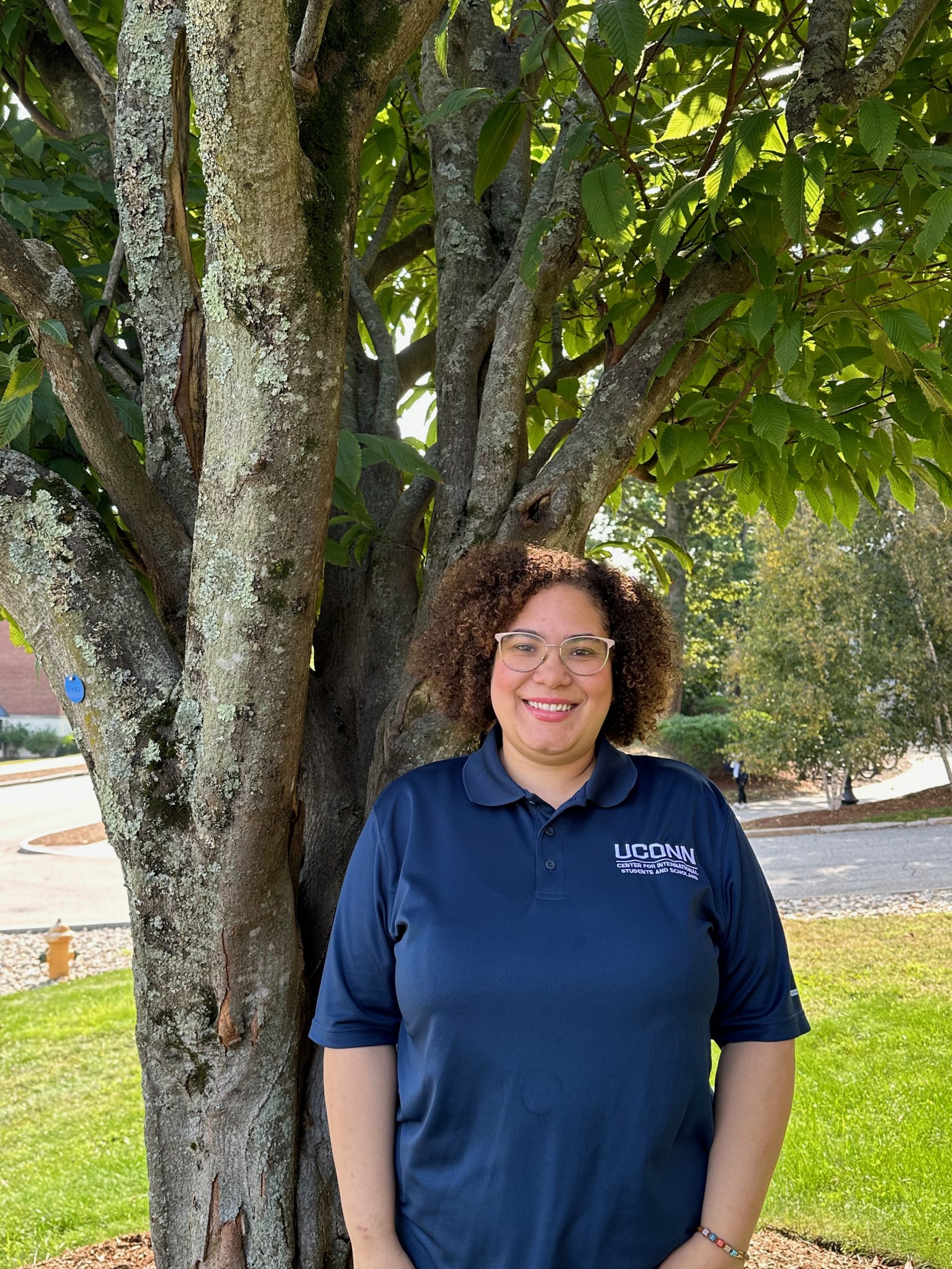 Ana Colon-Wallace headshot. Smiling next to tree on UConn campus.